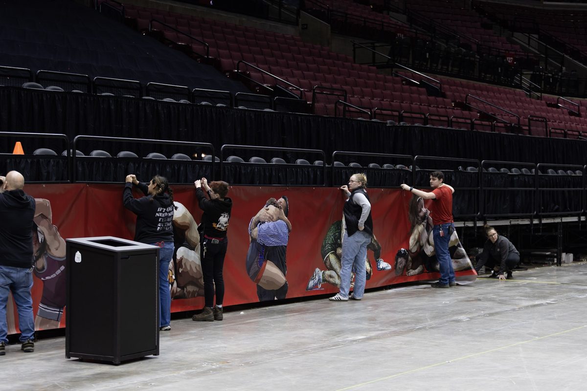 Crew putting up a wall of banners on an empty arena floor