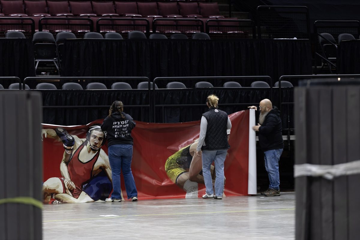Crew hanging large banners with rolled-up mats in the foreground