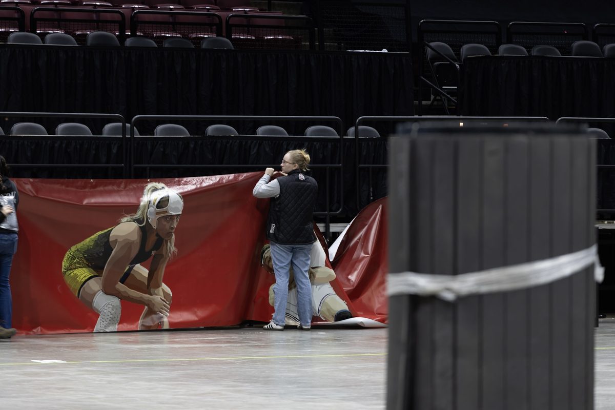 A crew member hanging a large banner beside rolled mats